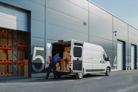 e-commerce and distance selling business: Shipping goods from the logistics warehouse Employee loads boxes into a delivery van at the loading bay for online and mail order businesses.