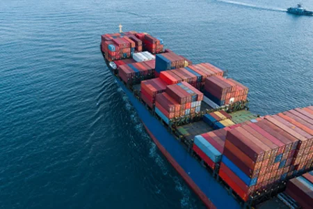 Technical trade: global flow of goods by container ship Container ship with colourful freight containers on the open sea as a symbol of technical trade.